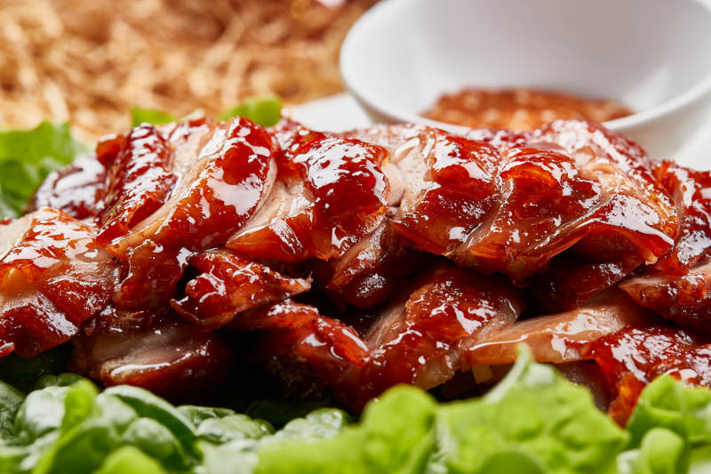 白色瓷盘装的蜜汁叉烧鸡腿肉图片