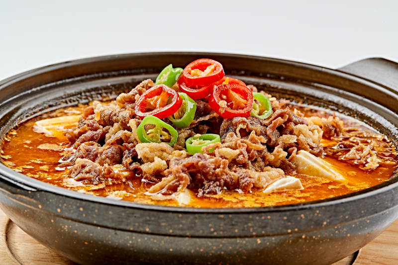 精美餐具装的砂锅香辣肥牛豆花图片