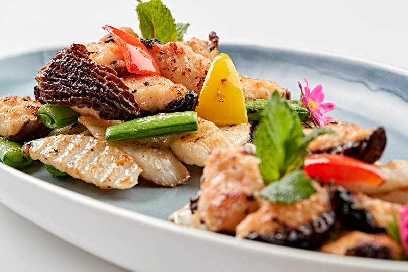 精美瓷盘装的黑胡椒彩椒蜜豆山药小炒羊肚菌图片