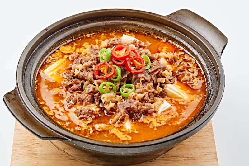 精美餐具装的砂锅香辣肥牛豆花图片