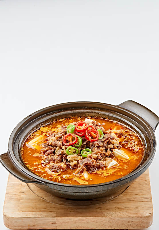 精美餐具装的砂锅香辣肥牛豆花图片