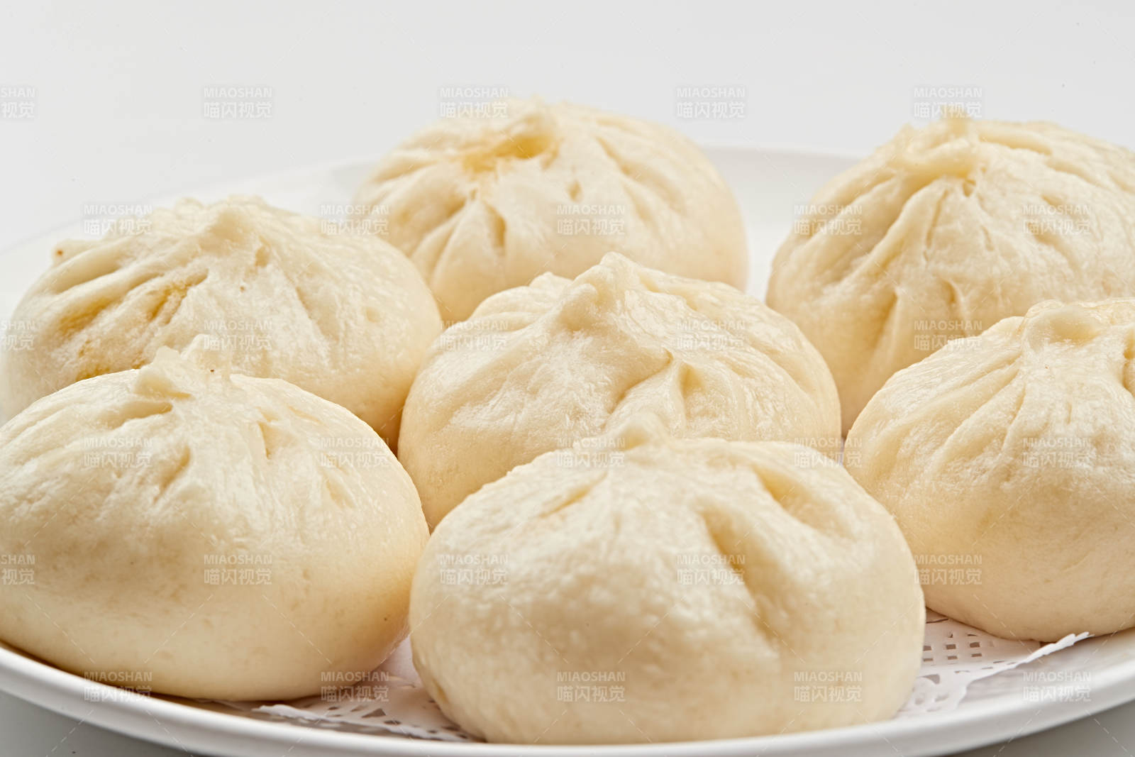 白色瓷盘装的熏肉馅料传统大包子图片