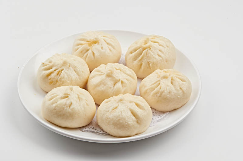 白色瓷盘装的熏肉馅料传统大包子图片