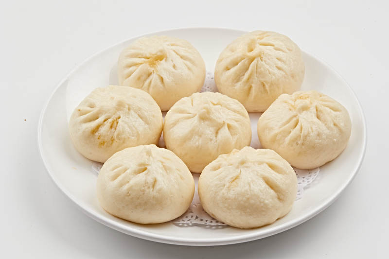 白色瓷盘装的熏肉馅料传统大包子图片