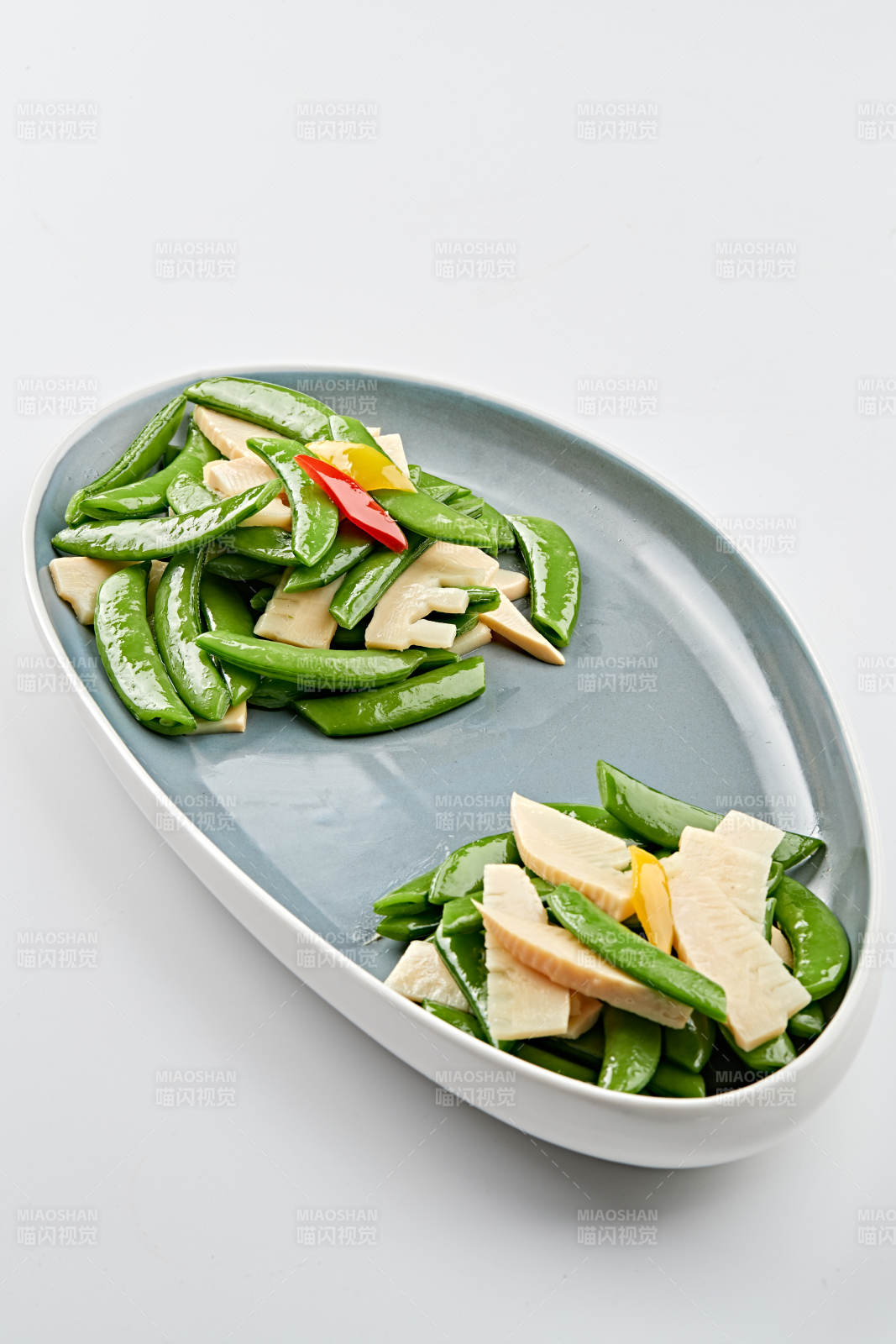 精美瓷盘装的冬笋彩椒炒蜜豆图片