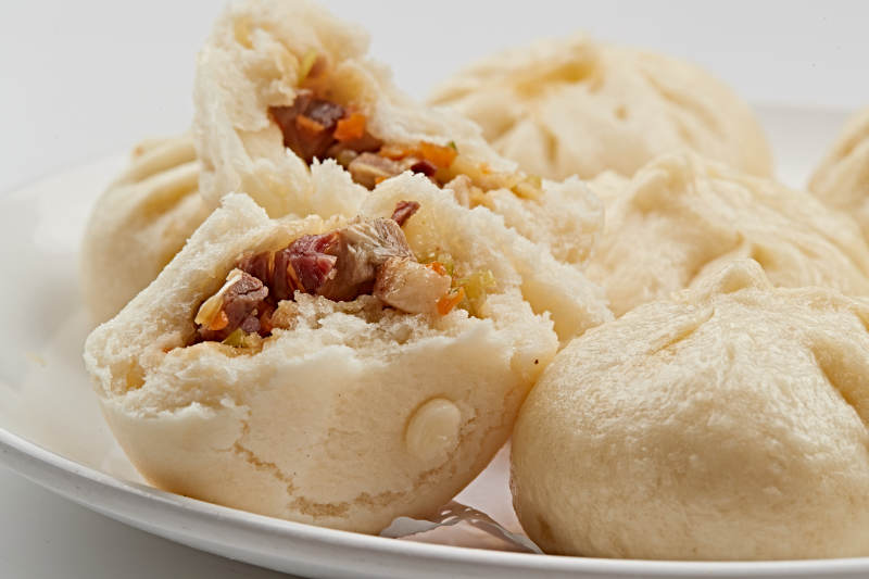 白色瓷盘装的熏肉馅料传统大包子图片