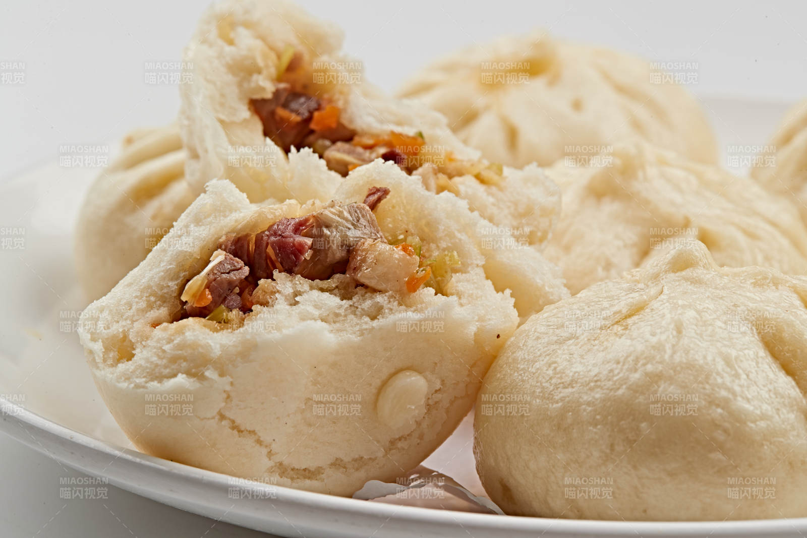 白色瓷盘装的熏肉馅料传统大包子图片