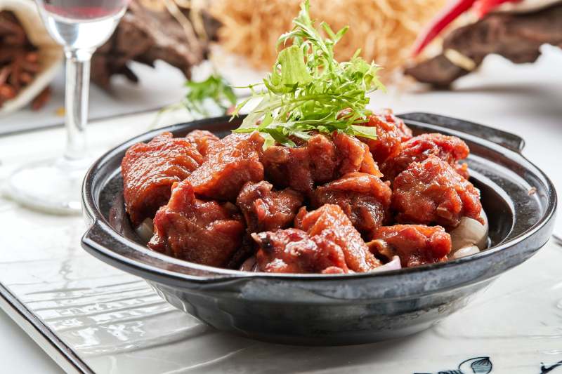 黑色砂锅装的葱香红烧鸡块图片