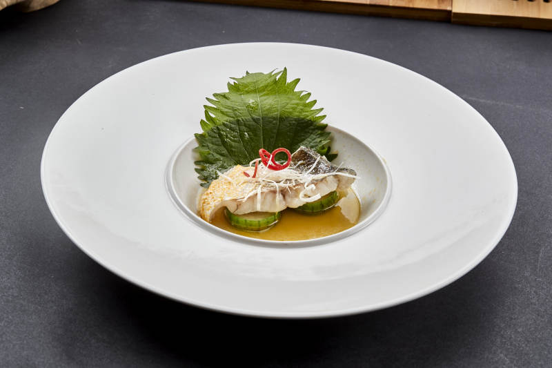 白色圆瓷盘装的位菜紫苏叶配鲜汤鱼块图片