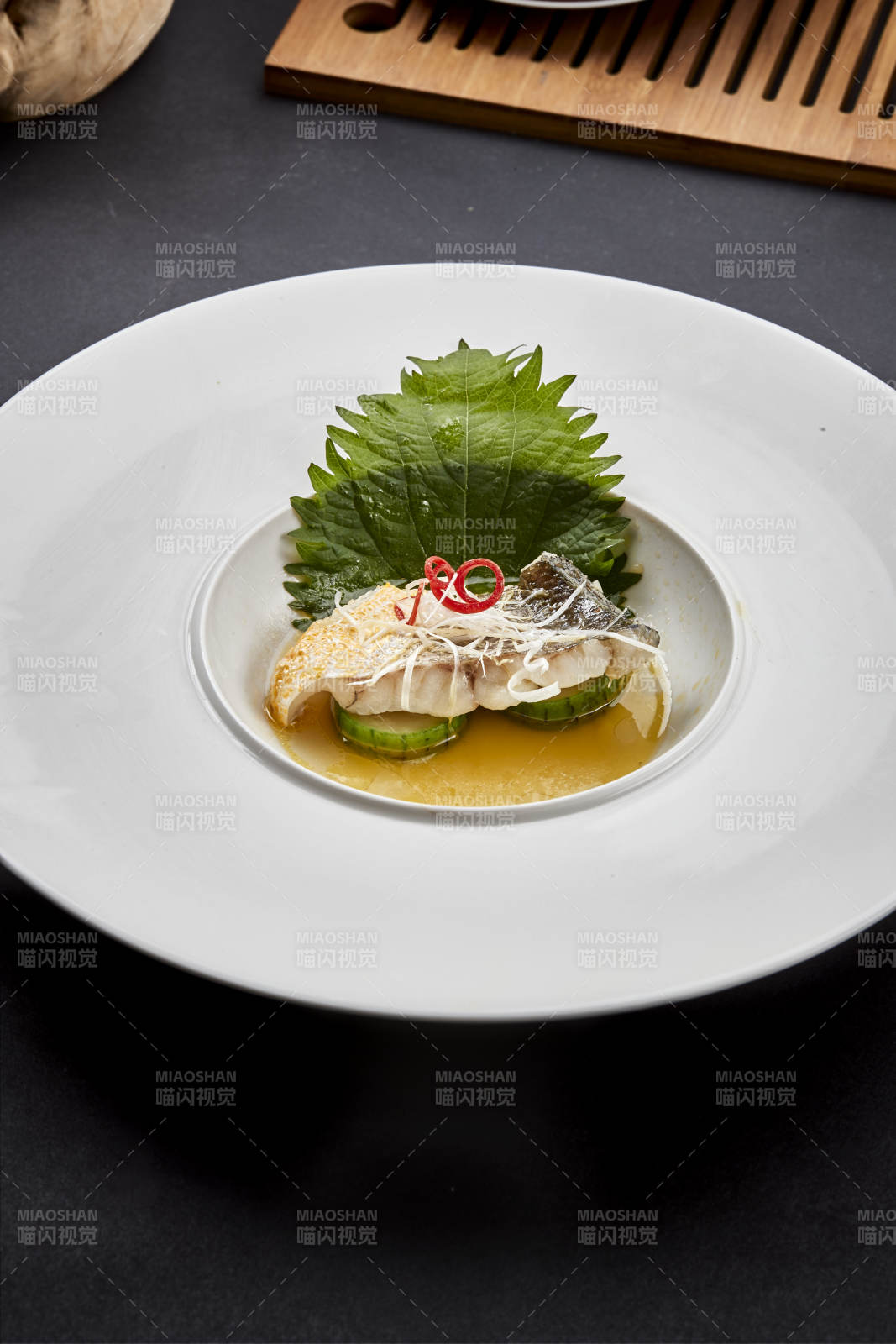 白色圆瓷盘装的位菜紫苏叶配鲜汤鱼块图片