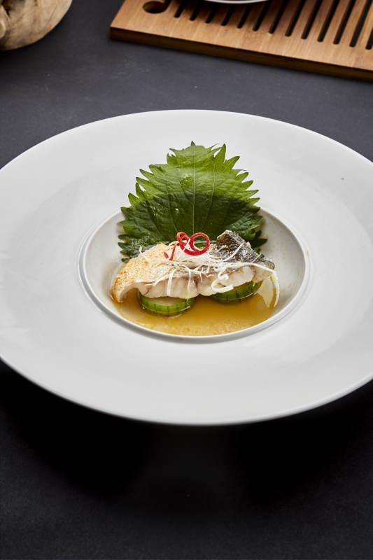 白色圆瓷盘装的位菜紫苏叶配鲜汤鱼块图片