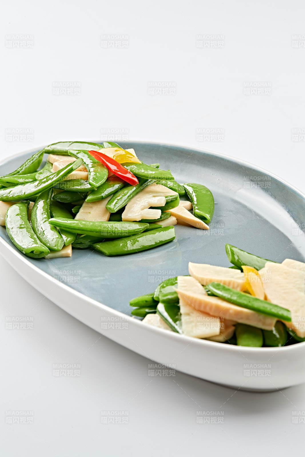精美瓷盘装的冬笋彩椒炒蜜豆图片