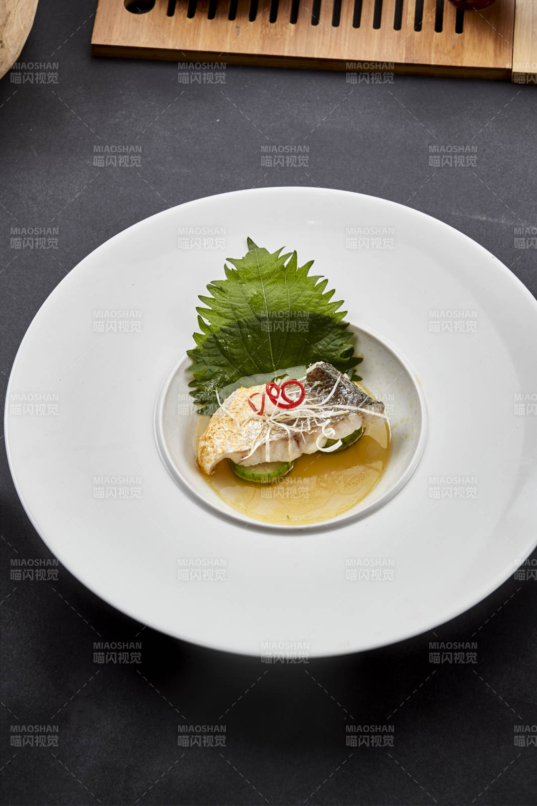 白色圆瓷盘装的位菜紫苏叶配鲜汤鱼块图片