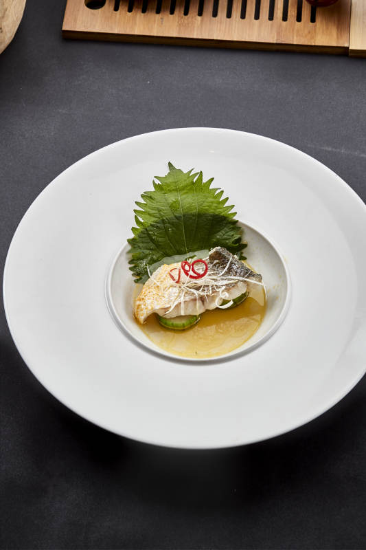 白色圆瓷盘装的位菜紫苏叶配鲜汤鱼块图片