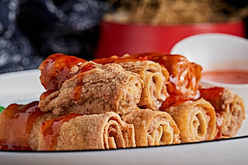 白色瓷盘装的浇汁油炸干豆腐卷图片