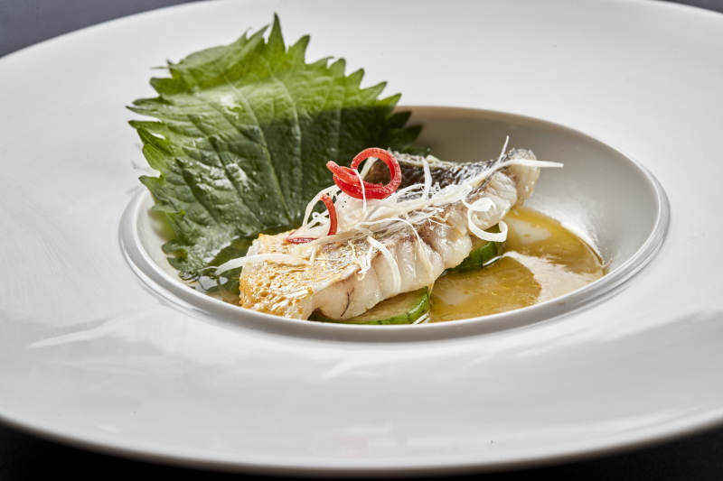 白色圆瓷盘装的位菜紫苏叶配鲜汤鱼块图片