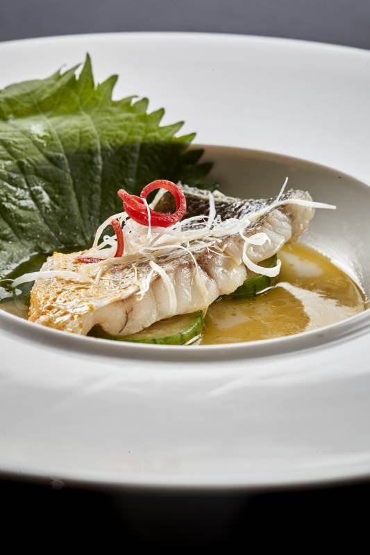 白色圆瓷盘装的位菜紫苏叶配鲜汤鱼块图片