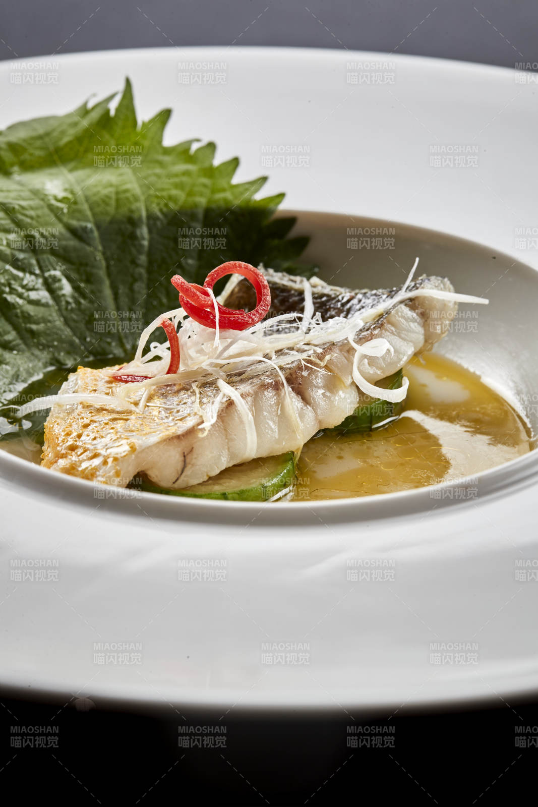 白色圆瓷盘装的位菜紫苏叶配鲜汤鱼块图片