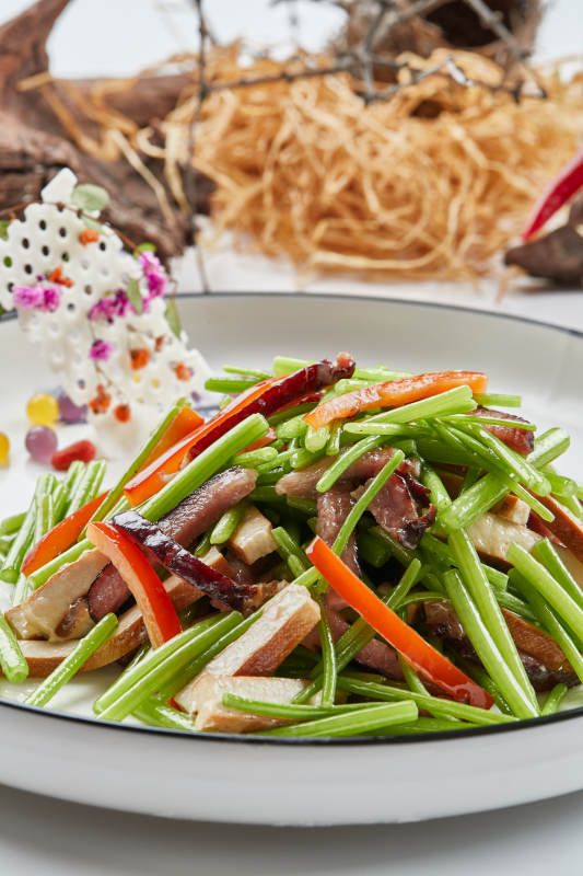 白色瓷盘装的腊肉彩椒茼蒿炒熏干子图片