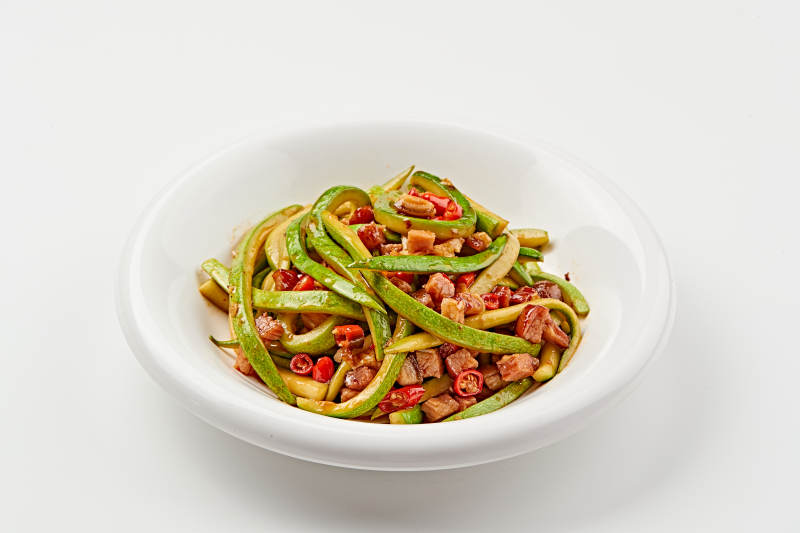 白色瓷盘装的葫芦条米椒炝炒腊肉丁图片