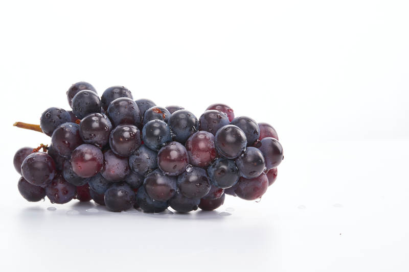 白色背景上摆放的水嫩新鲜紫葡萄图片