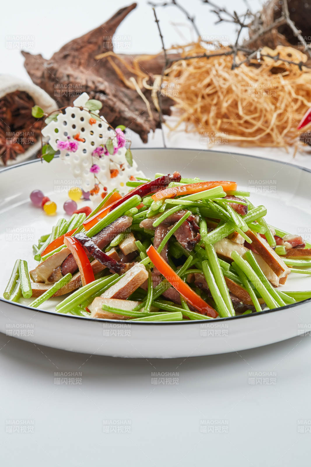 白色瓷盘装的腊肉彩椒茼蒿炒熏干子图片