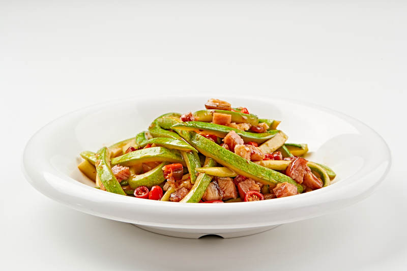 白色瓷盘装的葫芦条米椒炝炒腊肉丁图片