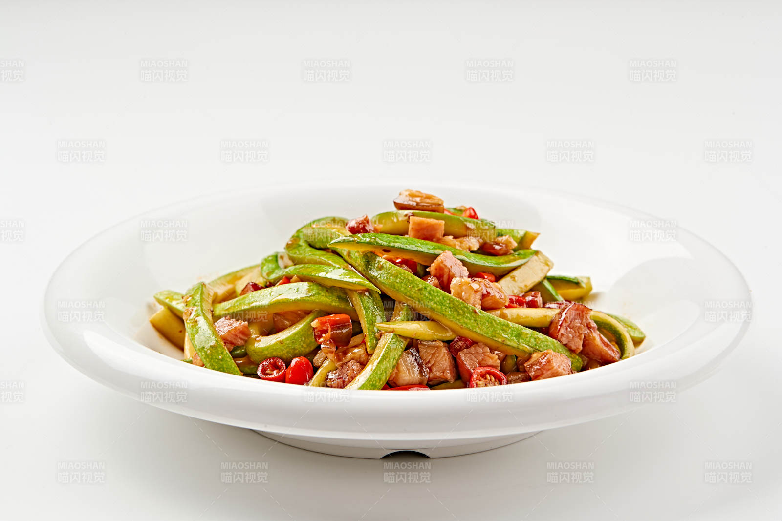 白色瓷盘装的葫芦条米椒炝炒腊肉丁图片