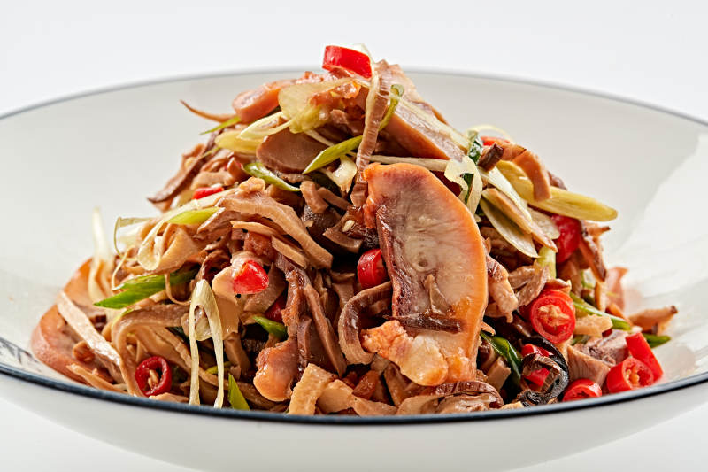 白色瓷盘装的香味小炒猪头肉图片