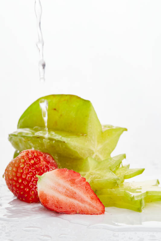 白色背景上摆放的新鲜洋桃和草莓及切片图片