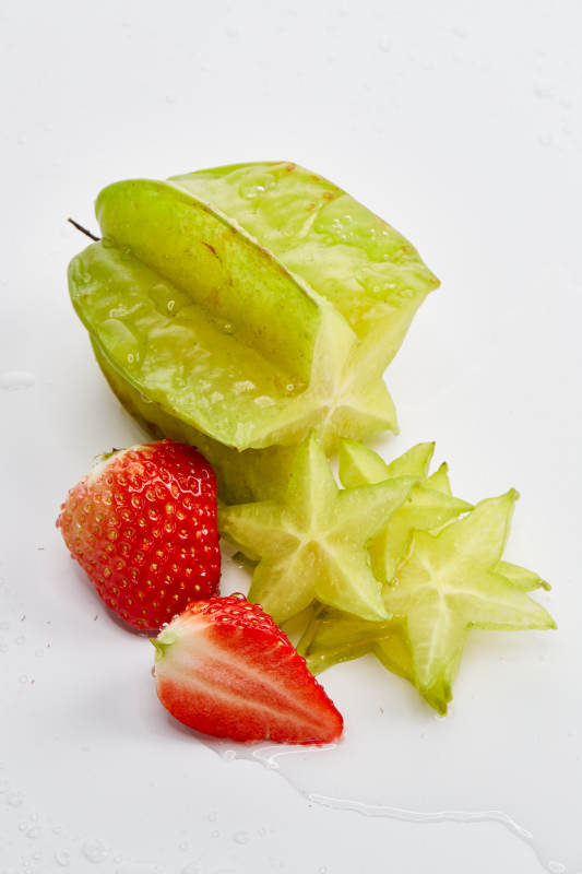 白色背景上摆放的新鲜洋桃和草莓及切片图片