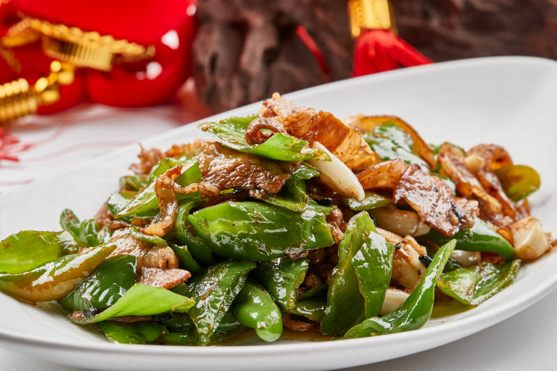 白色瓷盘装的杭椒小炒肉图片