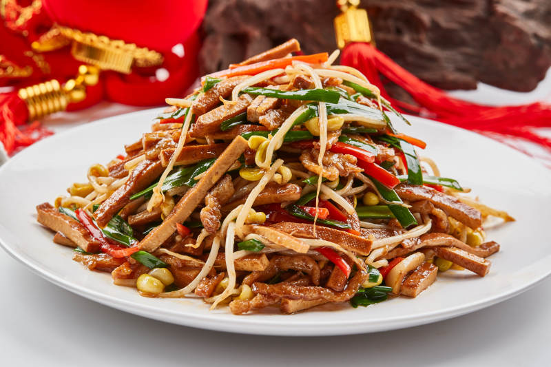 白色瓷盘装的彩椒丝黄豆芽拌香干图片