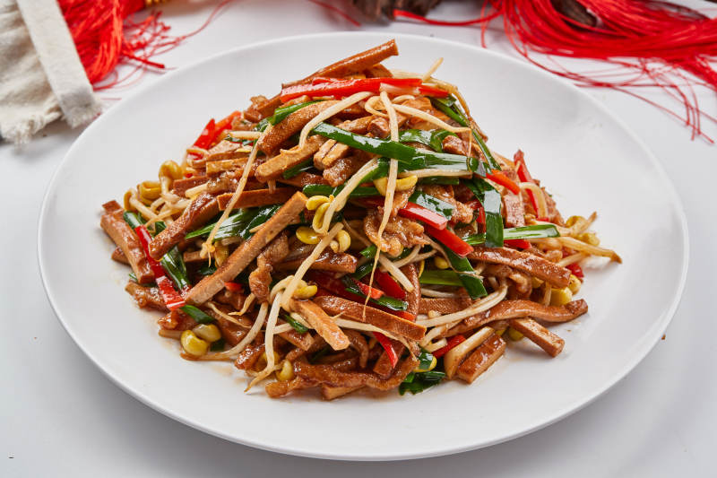 白色瓷盘装的彩椒丝黄豆芽拌香干图片