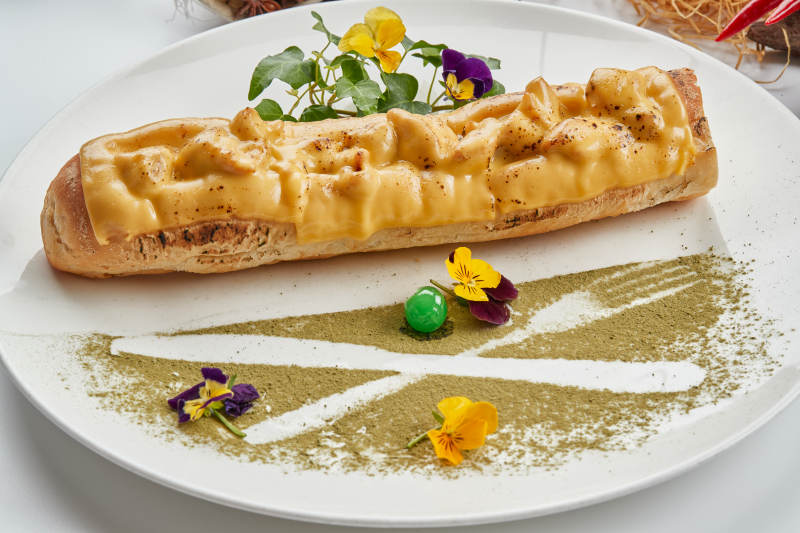 白色瓷盘装的的芝士火腿焗法棍面包图片