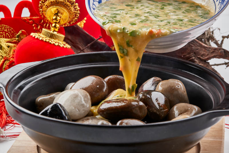 黑色砂锅装的创意美食鸡蛋碰石头图片