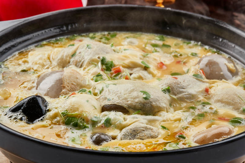 黑色砂锅装的创意美食鸡蛋碰石头图片