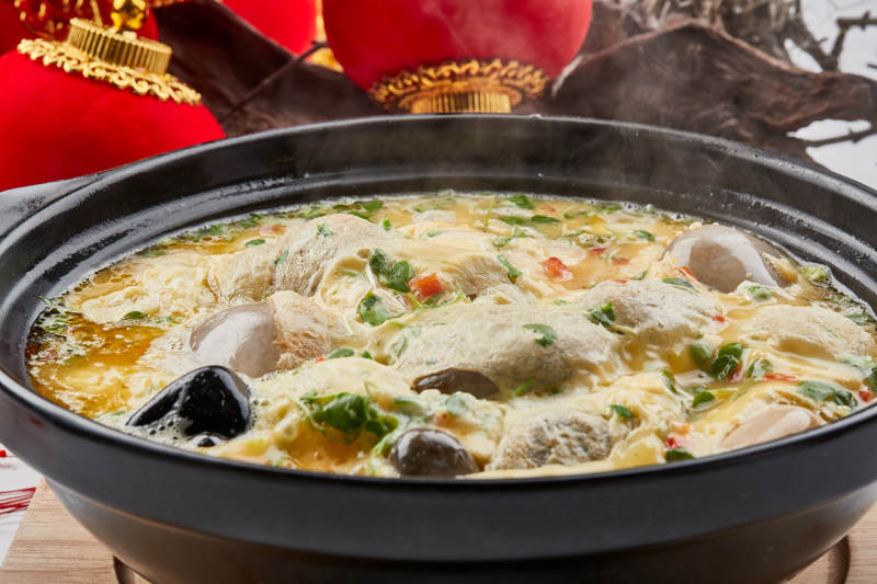 黑色砂锅装的创意美食鸡蛋碰石头图片