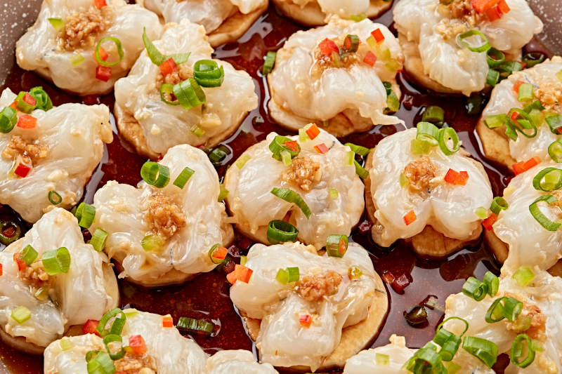 石盘器皿装的葱香油爆大虾仁图片