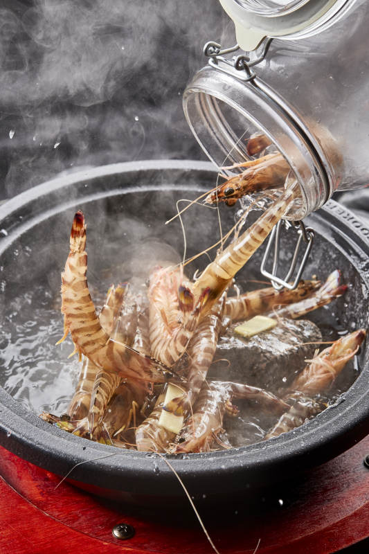 用加热的火山岩石烹煮的新鲜基围虾岩烧图片