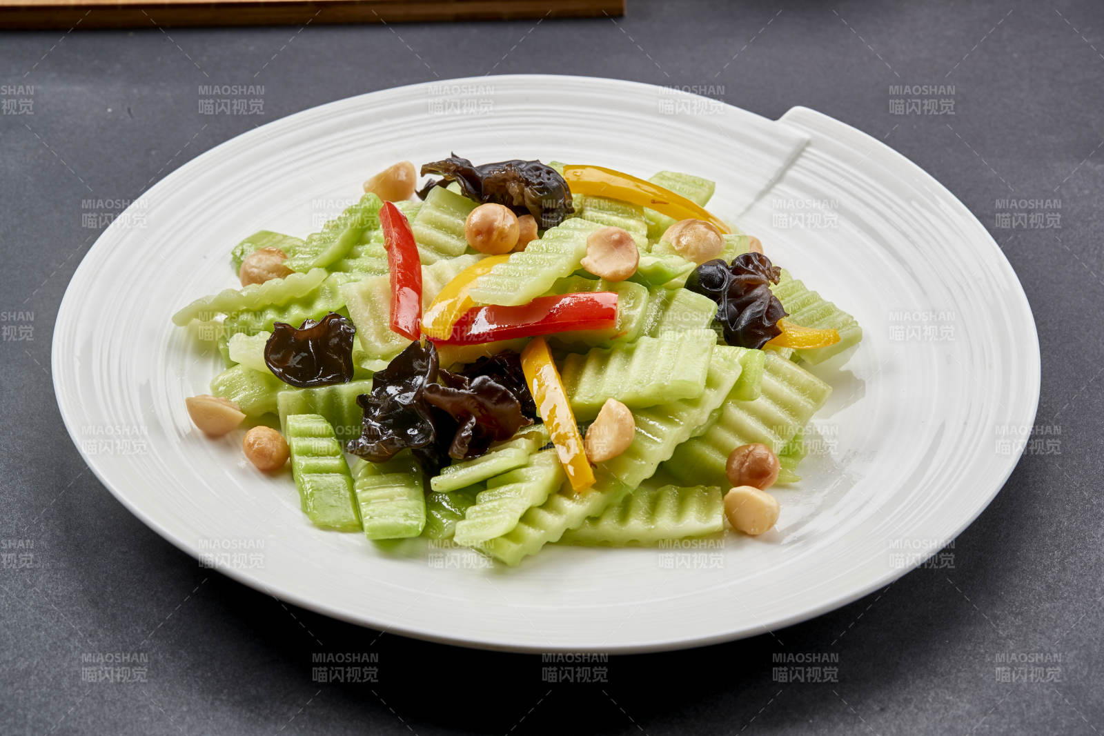 圆瓷盘装的彩椒木耳乳瓜炒银杏图片