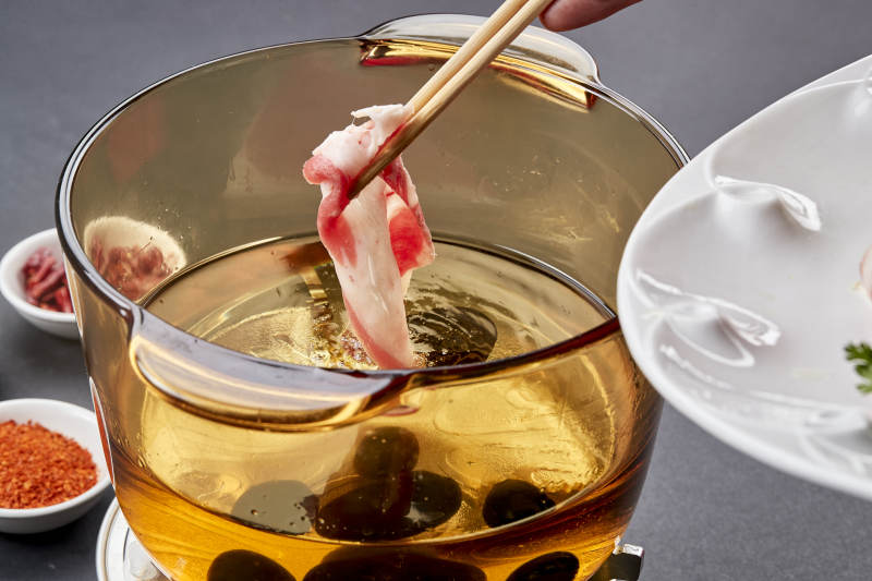 向岩石加热的沸腾食用油中投放鲜美肥牛片图片