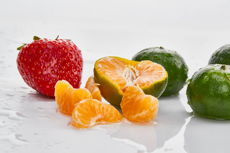 白色背景上摆放的小青柑与草莓图片