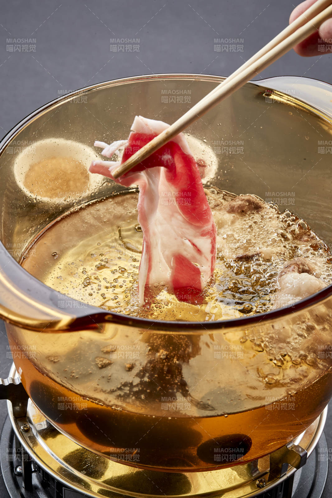 向岩石加热的沸腾食用油中投放鲜美肥牛片图片