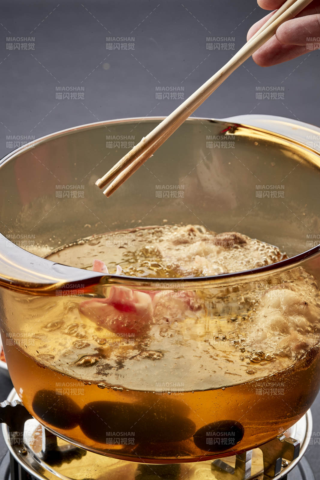 向岩石加热的沸腾食用油中投放鲜美肥牛片图片