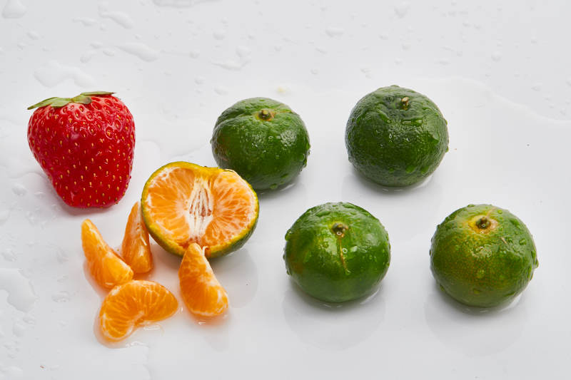 白色背景上摆放的小青柑与草莓图片