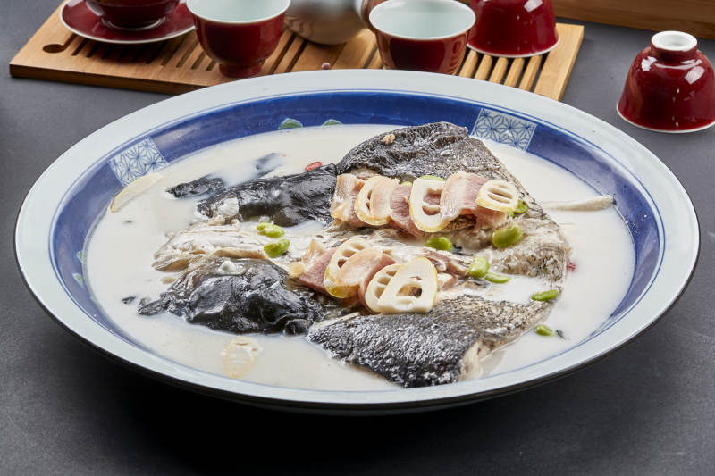 青花瓷盘装的高级奶汤腌笃鲜炖大鲢鱼头图片