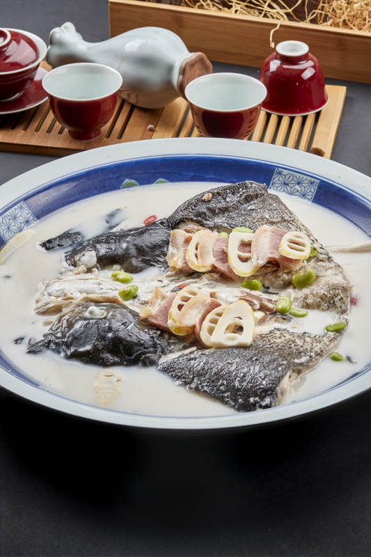 青花瓷盘装的高级奶汤腌笃鲜炖大鲢鱼头图片