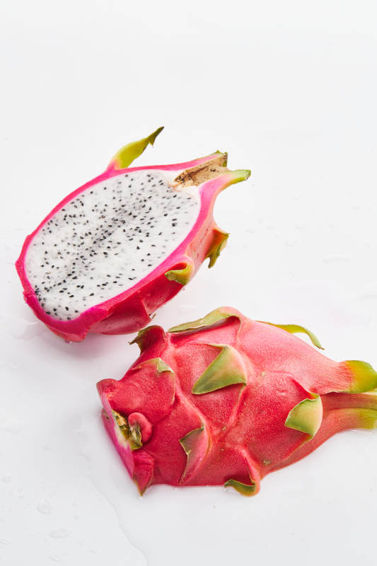 白色背景上摆放切开的新鲜火龙果图片
