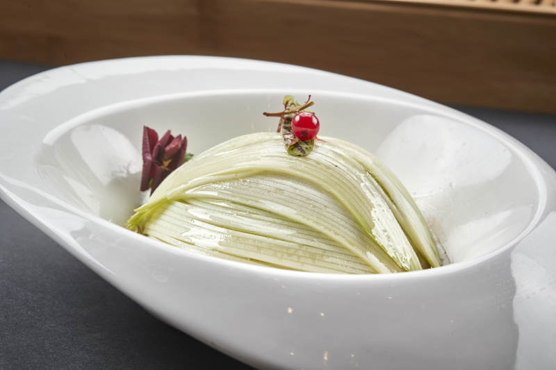 白色椭圆瓷盘装的凉拌浇汁西芹丝图片